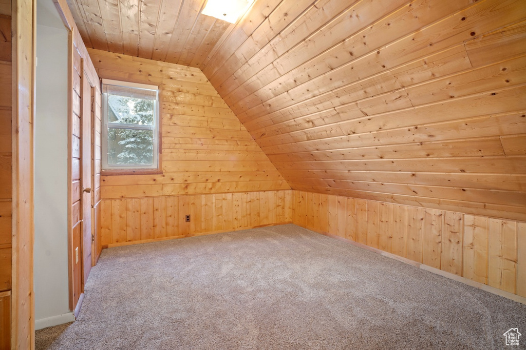 Additional living space featuring wooden walls, wood ceiling, carpet, and vaulted ceiling