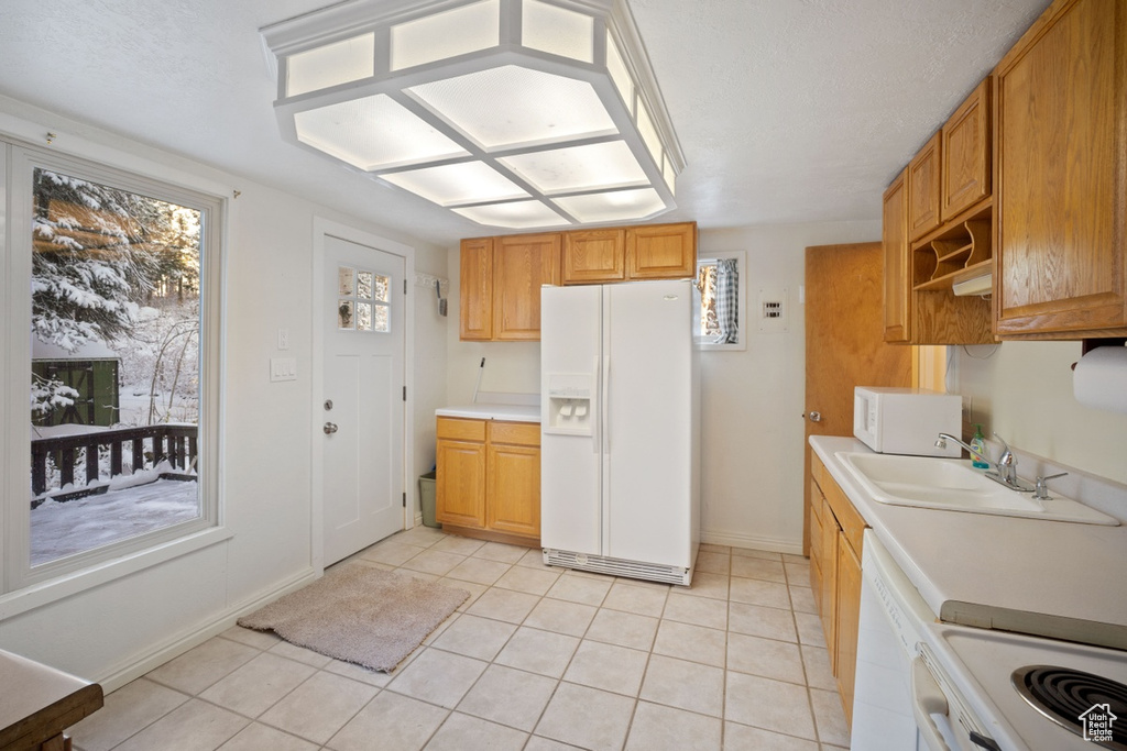 Kitchen with white appliances, light tile patterned floors, light countertops, and a sink