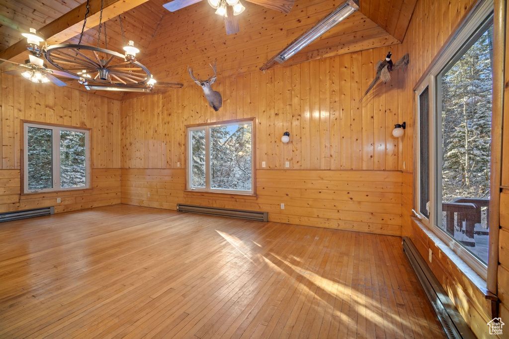 Unfurnished room with a baseboard heating unit, ceiling fan, wood walls, wood-type flooring, and baseboard heating