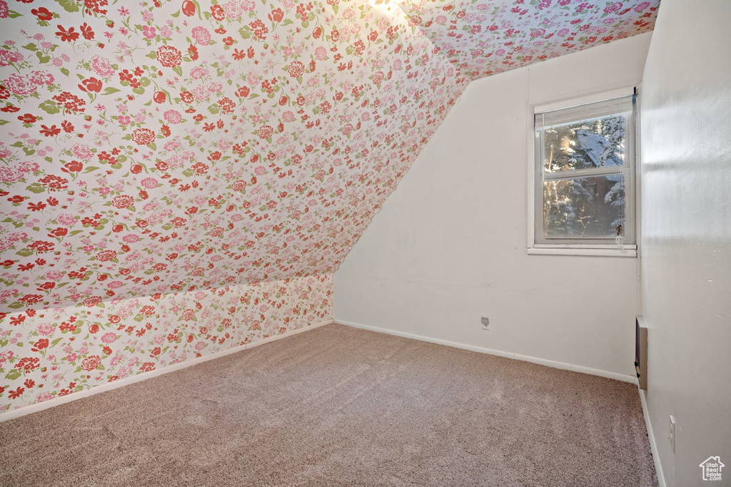 Carpeted empty room with lofted ceiling and baseboards