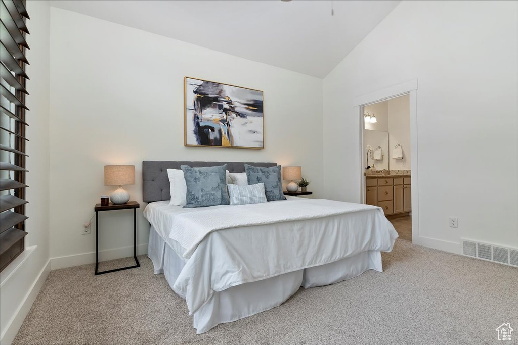 Carpeted bedroom with vaulted ceiling, baseboards, and connected bathroom