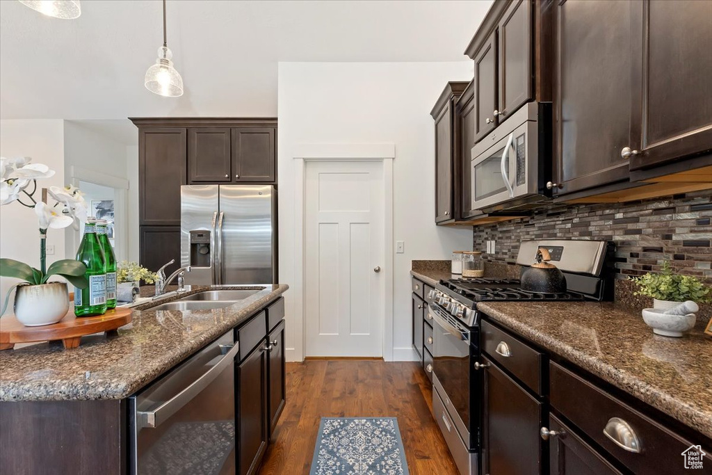 Kitchen featuring stainless steel appliances, a sink, dark brown cabinets, and backsplash