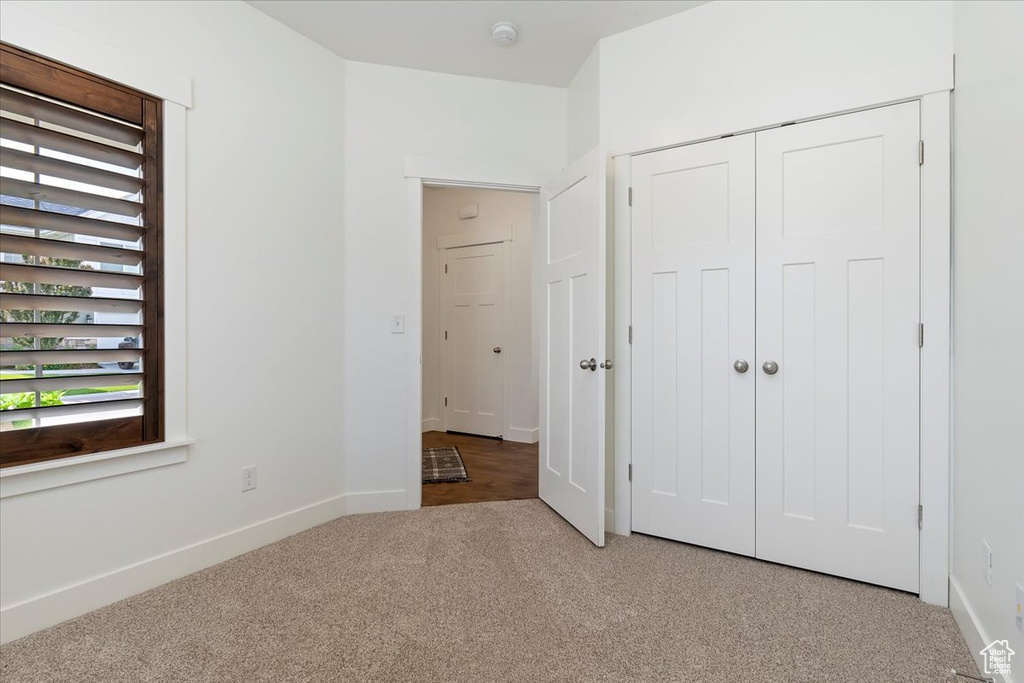 Unfurnished bedroom featuring light carpet, baseboards, and a closet