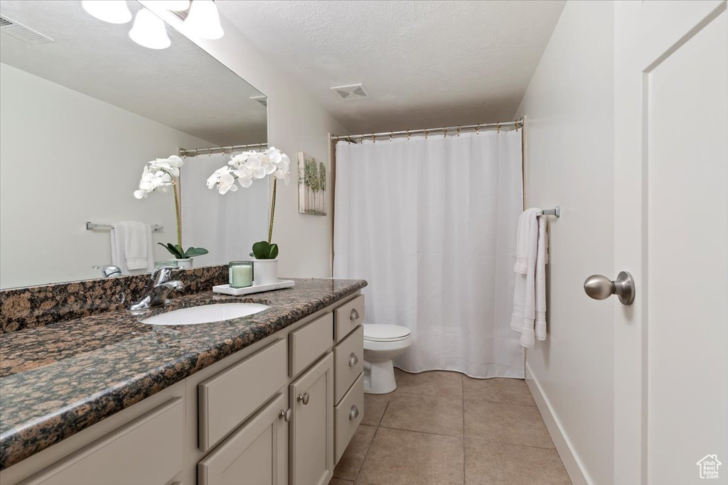 Full bath featuring vanity, toilet, tile patterned floors, baseboards, and a shower with shower curtain