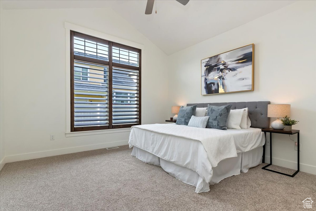 Carpeted bedroom with lofted ceiling, baseboards, and a ceiling fan