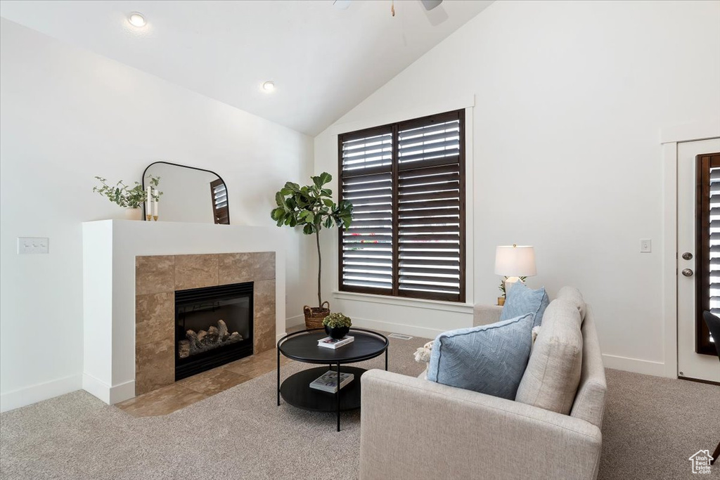 Carpeted living room with vaulted ceiling, a fireplace, ceiling fan, and baseboards