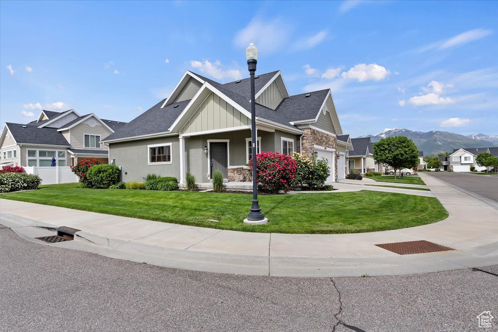 Craftsman-style house with a front yard, board and batten siding, a mountain view, stone siding, and driveway