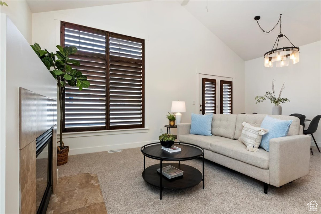 Living room with carpet floors, plenty of natural light, a glass covered fireplace, baseboards, and high vaulted ceiling