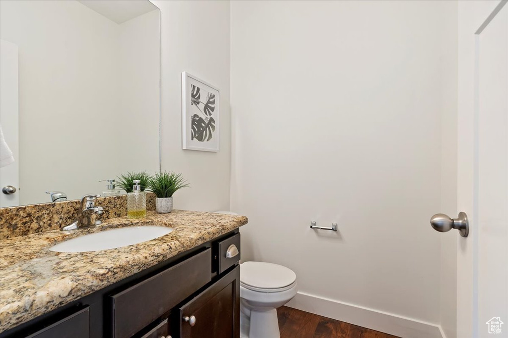 Bathroom featuring vanity, baseboards, toilet, and wood finished floors