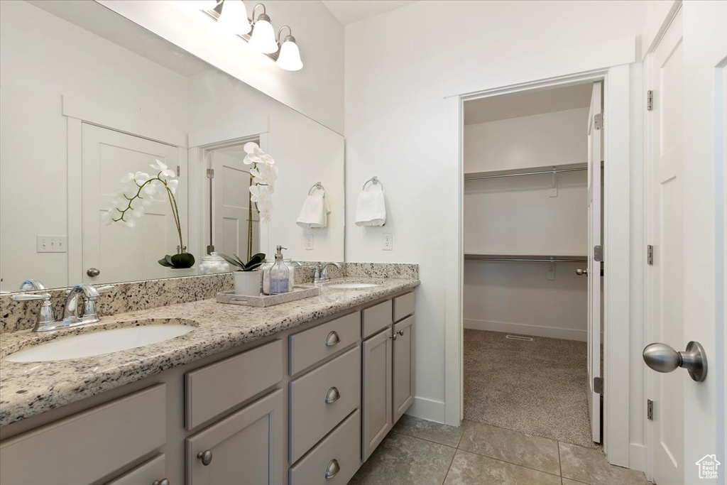 Full bathroom featuring double vanity, tile patterned floors, baseboards, and a spacious closet