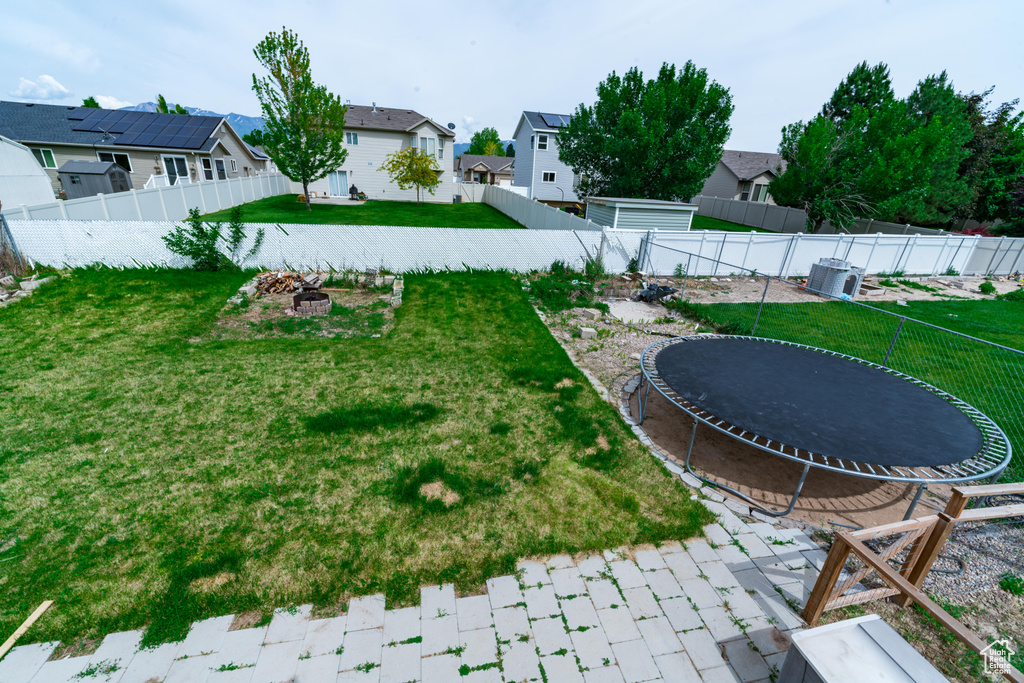 View of yard with a trampoline, an outdoor fire pit, and a residential view