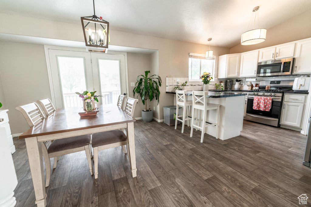 Dining room featuring dark wood-style floors, lofted ceiling, and baseboards