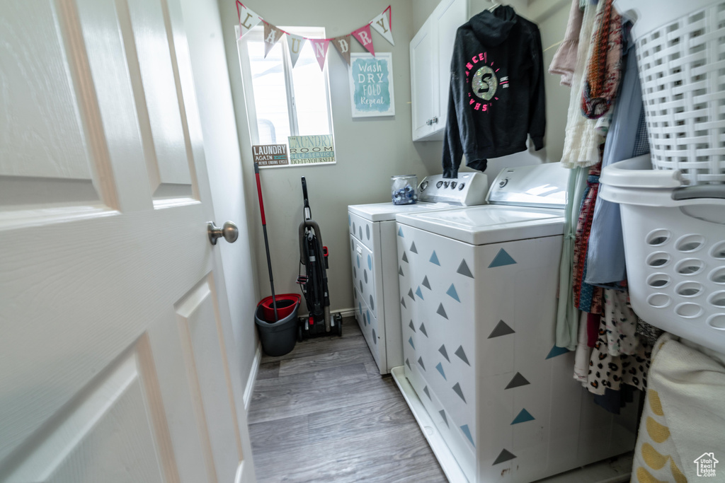 Washroom with cabinet space, separate washer and dryer, and light wood finished floors