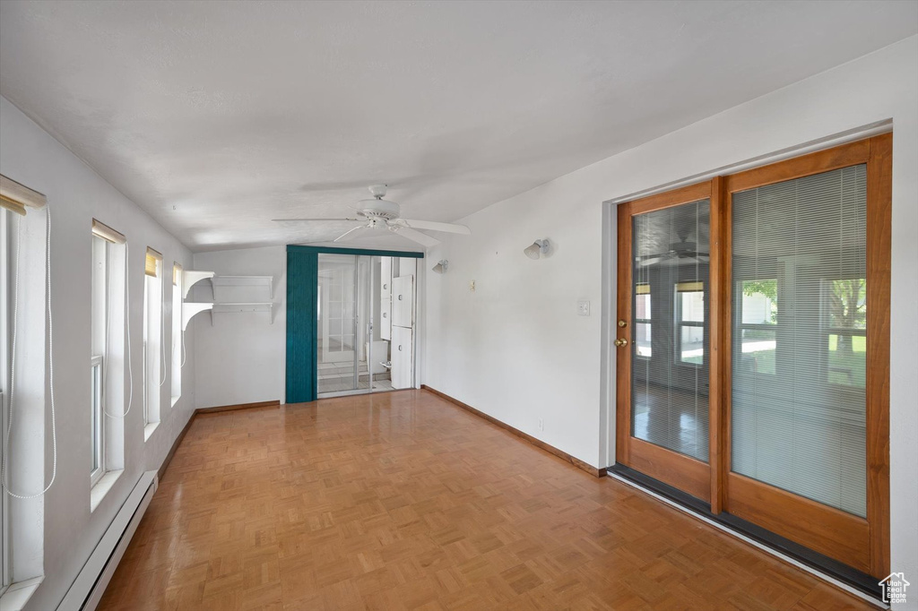Spare room with a baseboard radiator, a ceiling fan, healthy amount of natural light, and baseboards