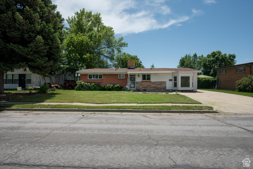 Ranch-style home with a front lawn, concrete driveway, a chimney, and brick siding