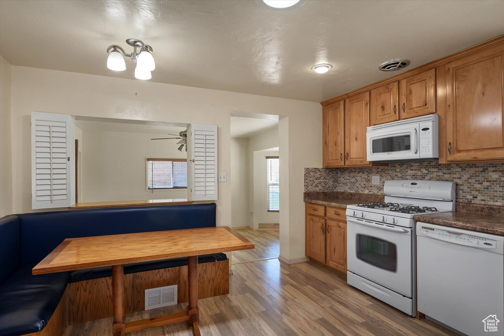 Kitchen featuring white appliances, backsplash, light wood finished floors, and brown cabinetry