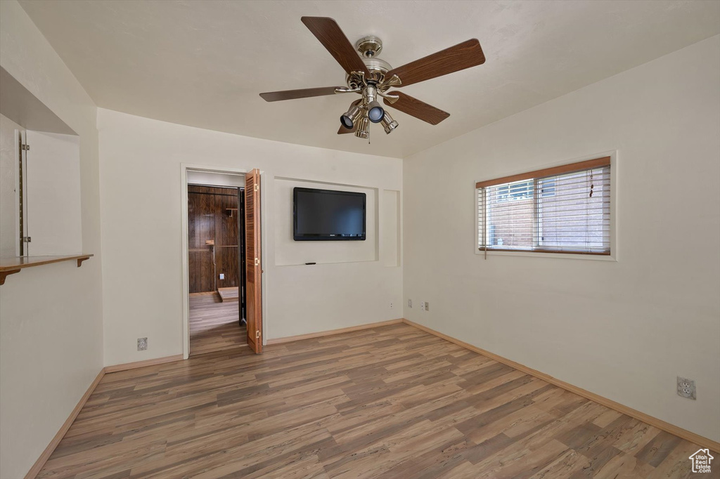 Unfurnished room featuring wood finished floors, a ceiling fan, and baseboards