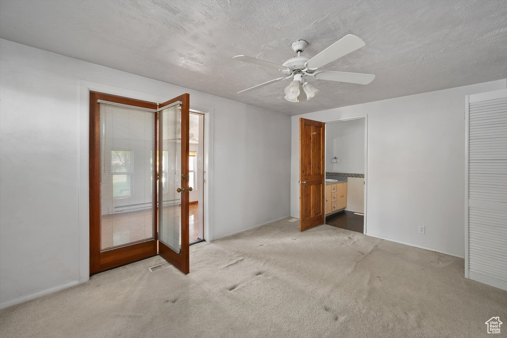 Unfurnished bedroom with carpet, ceiling fan, french doors, ensuite bath, and baseboards
