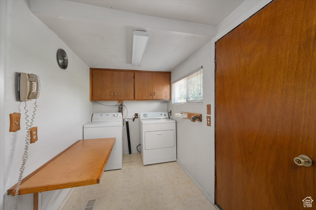 Laundry area featuring cabinet space, washing machine and clothes dryer, light floors, and baseboards