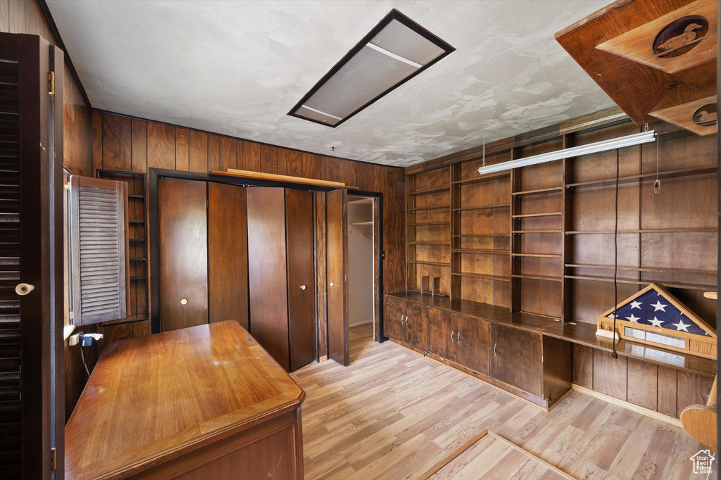 Unfurnished office featuring wood walls, wood finished floors, and built in shelves