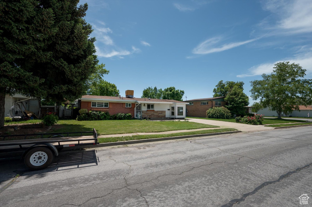 Ranch-style house with a front yard, brick siding, and a chimney