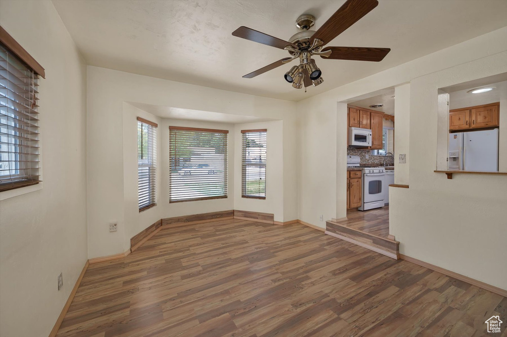 Unfurnished living room with wood finished floors, baseboards, and ceiling fan