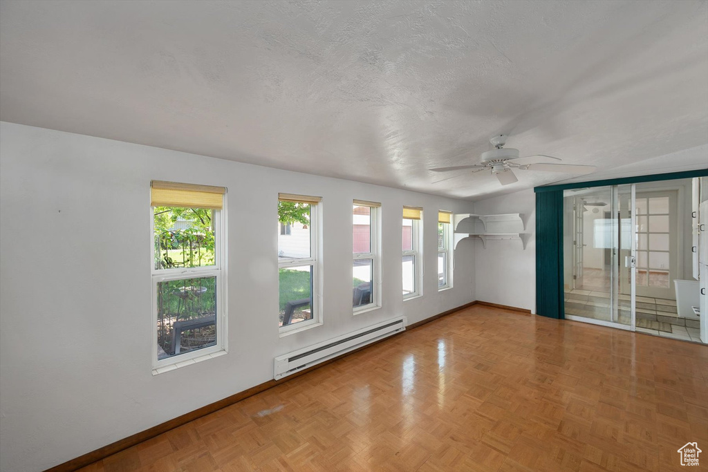 Empty room with baseboard heating, ceiling fan, and baseboards