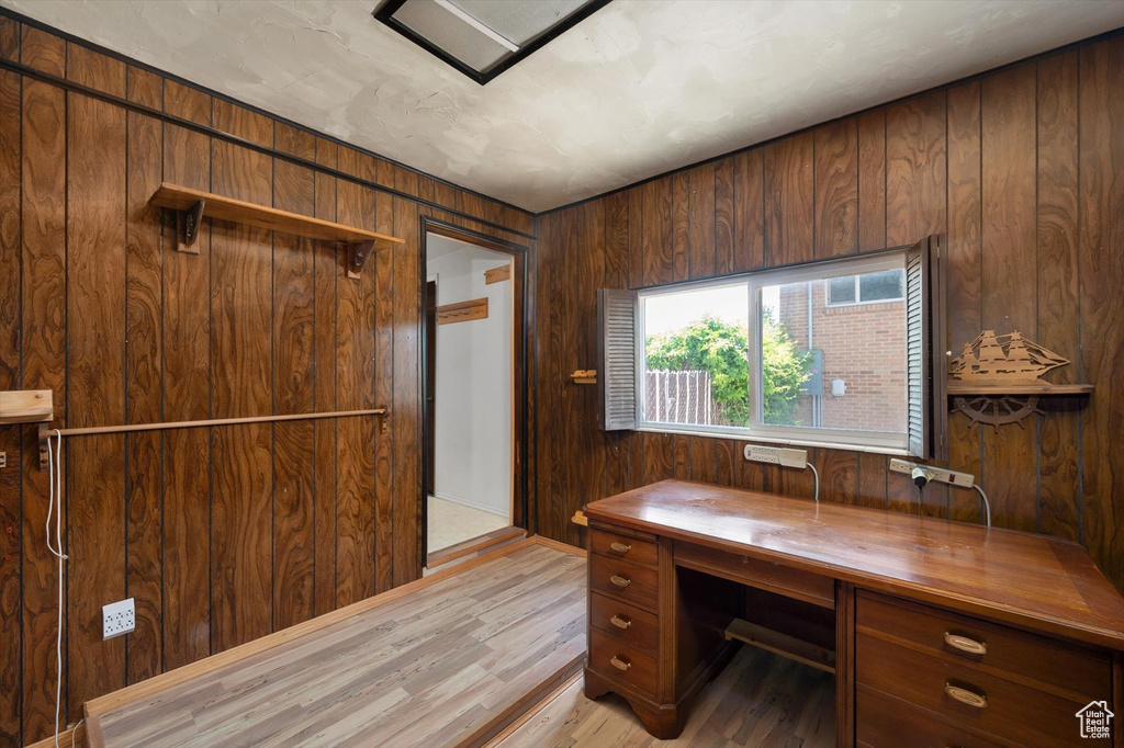 Home office with wooden walls and light wood-style floors