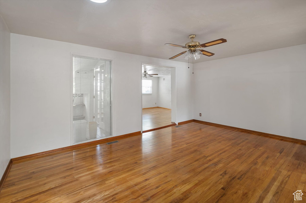 Empty room featuring wood finished floors, a ceiling fan, and baseboards