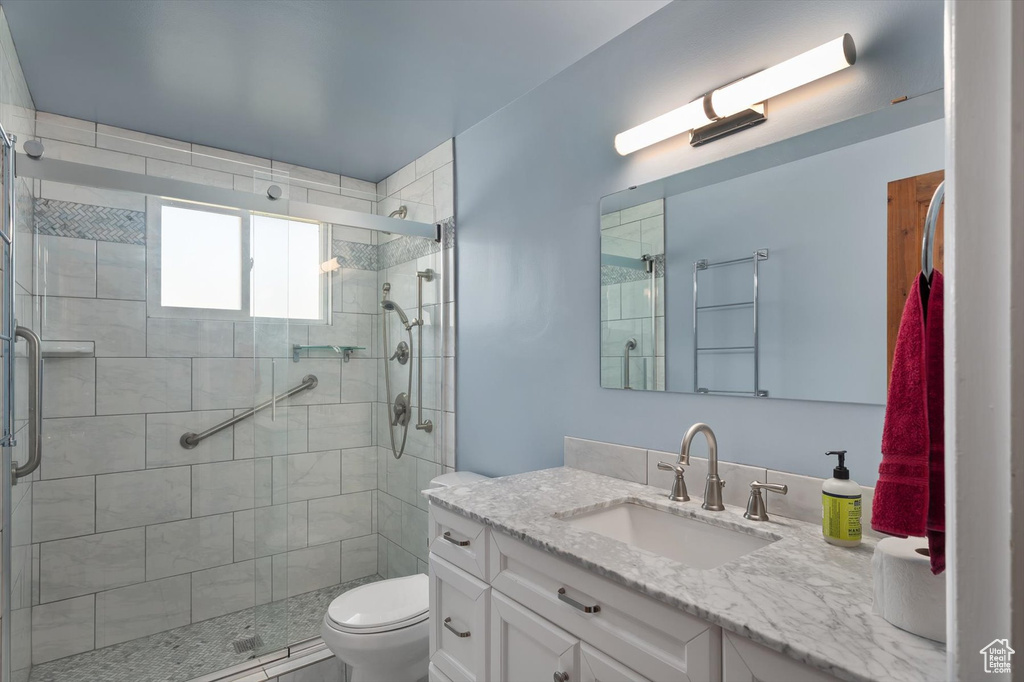 Bathroom featuring vanity, toilet, and a shower stall
