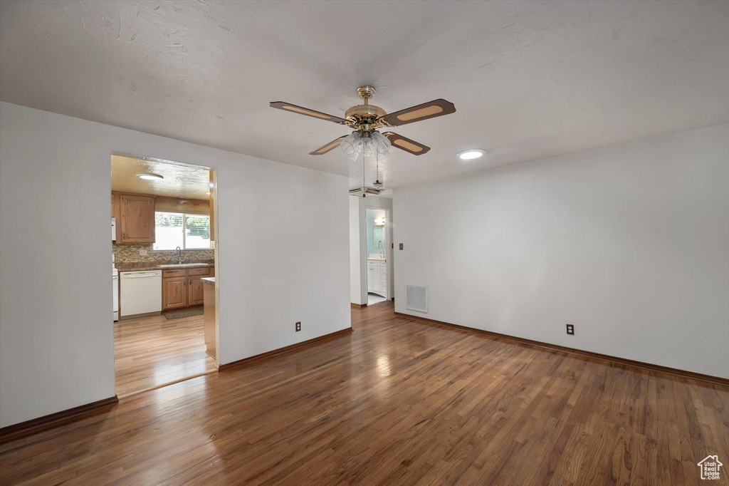 Unfurnished living room featuring wood finished floors, ceiling fan, and baseboards