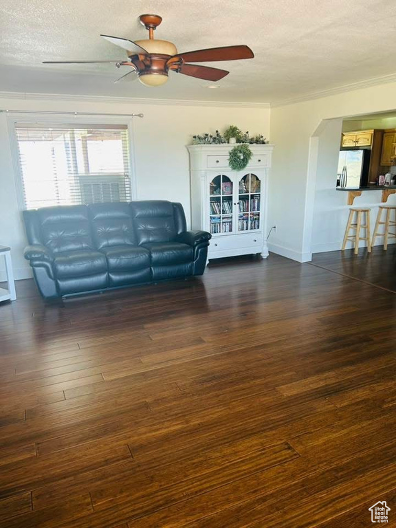 Living area featuring a textured ceiling, a ceiling fan, dark wood-style flooring, arched walkways, and baseboards