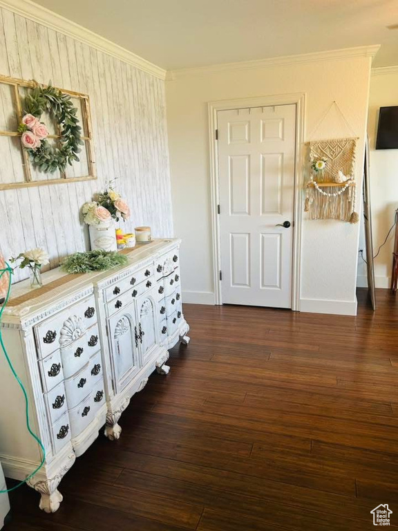 Bedroom with crown molding, dark wood-style floors, baseboards, and wood walls