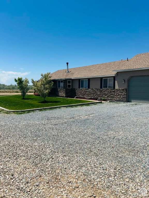 Ranch-style house featuring a garage, stone siding, and a front yard