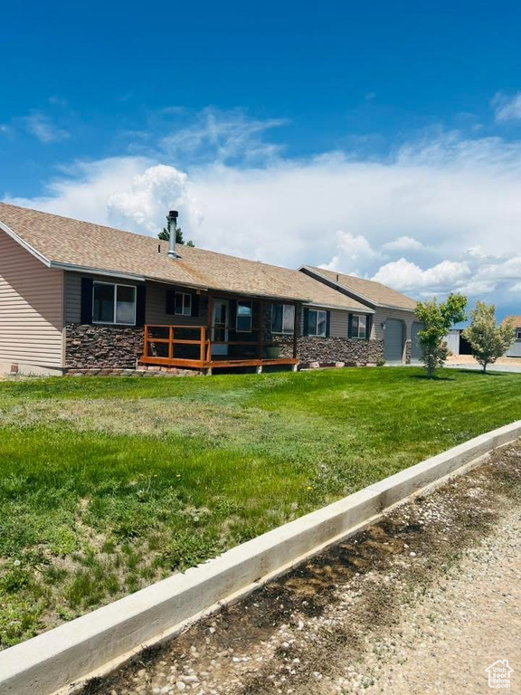 View of front of house featuring a deck, a front yard, and stone siding