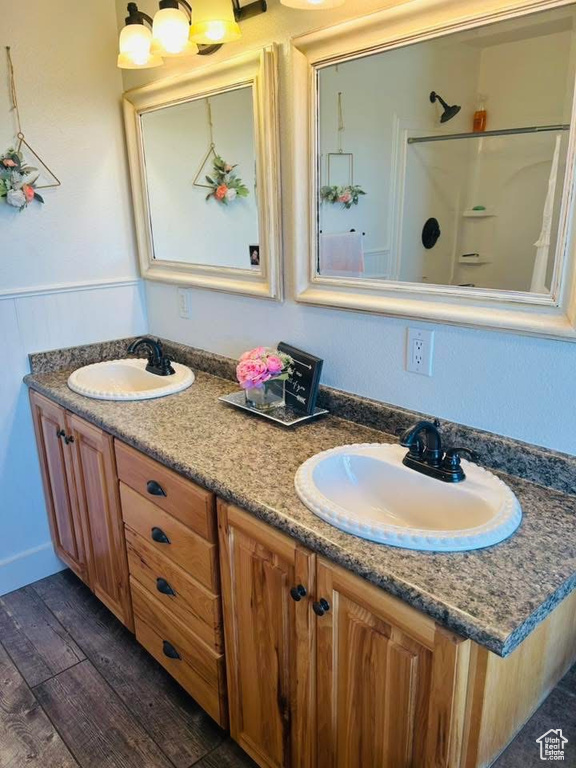 Full bath with double vanity, wood finished floors, and a shower