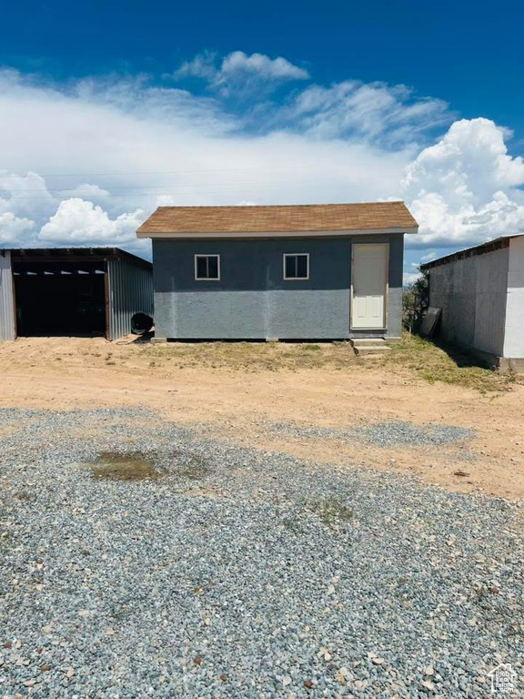 View of front facade featuring an outbuilding, stucco siding, and a pole building