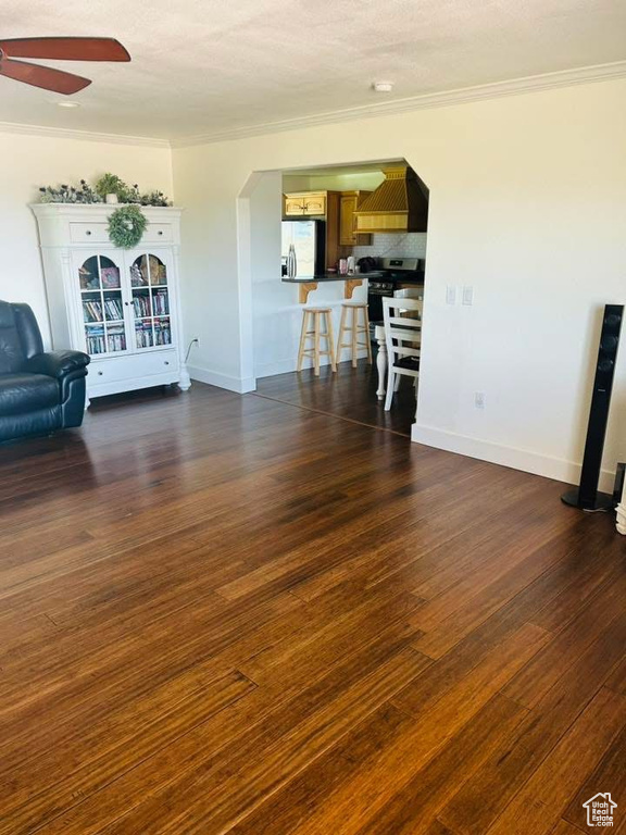 Living area with a ceiling fan, crown molding, dark wood finished floors, arched walkways, and baseboards