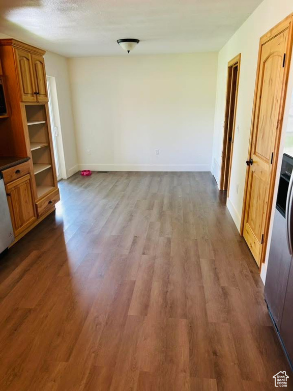 Unfurnished dining area with baseboards and dark wood-style floors