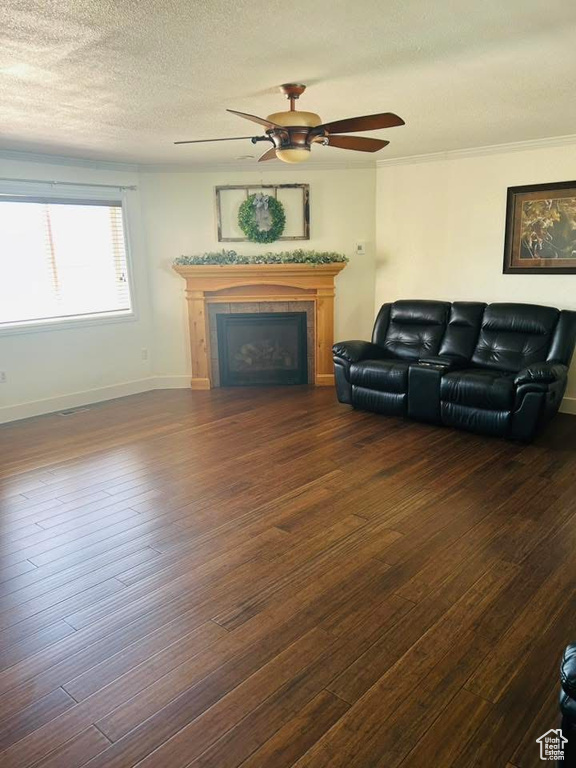 Living area featuring a ceiling fan, a fireplace, wood finished floors, a textured ceiling, and baseboards