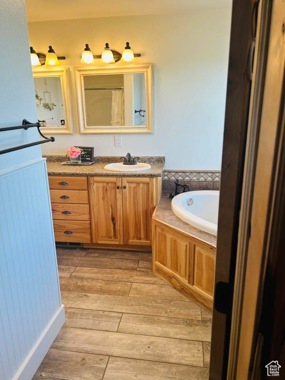 Full bathroom with vanity, hardwood / wood-style flooring, and a bath