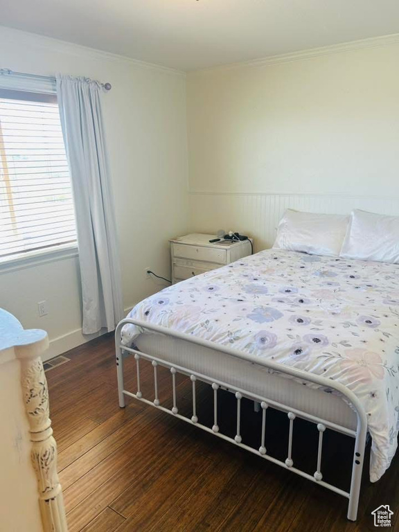 Bedroom with wood finished floors, crown molding, and baseboards