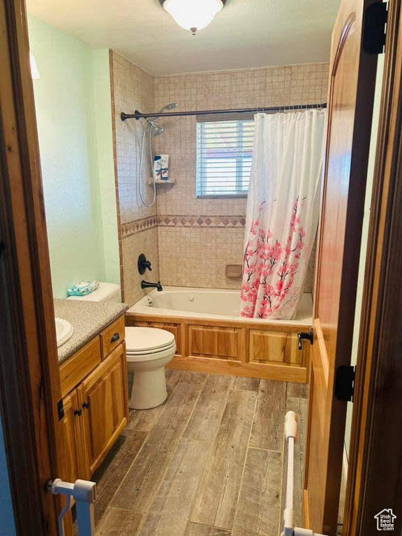 Full bathroom with hardwood / wood-style floors, shower / tub combo, toilet, and vanity