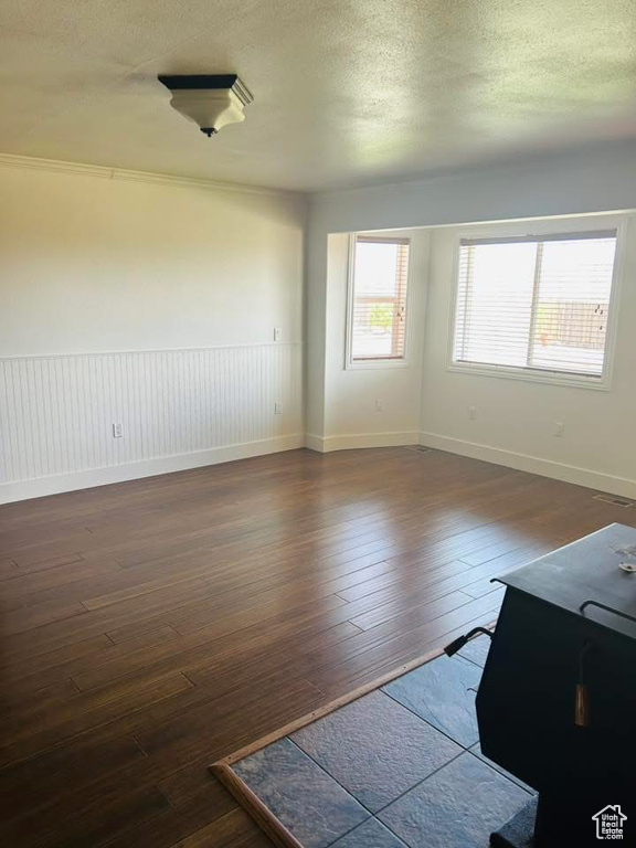 Spare room with dark wood-style flooring, a textured ceiling, and baseboards