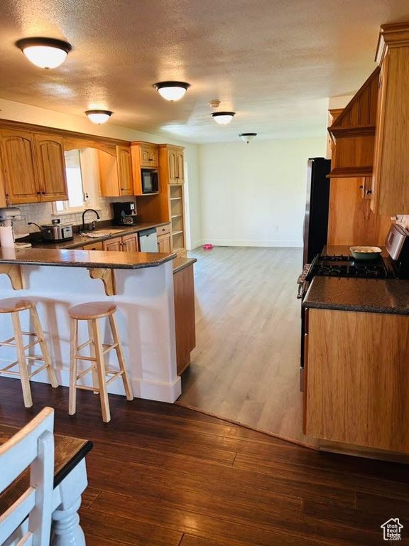 Kitchen with black microwave, freestanding refrigerator, dark countertops, dishwasher, and a sink