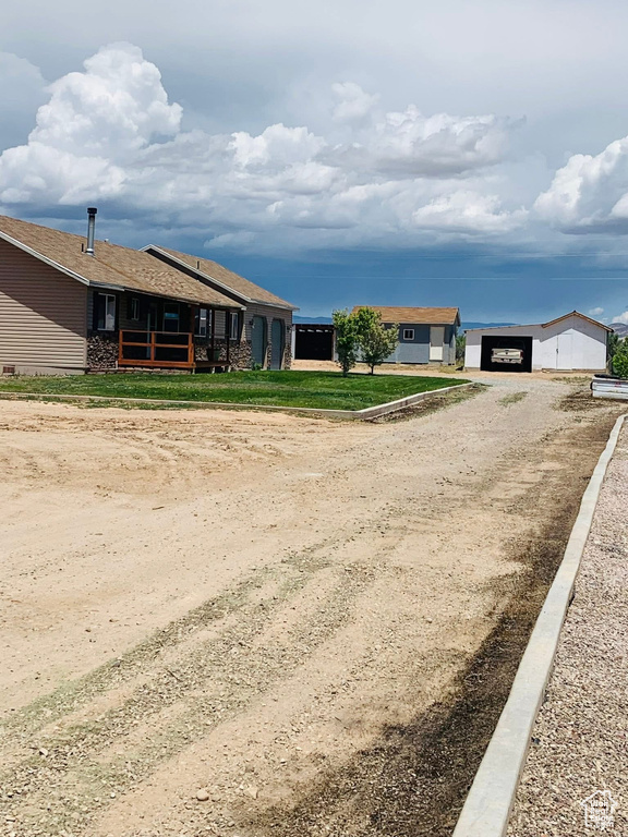 View of front of house with dirt driveway and a detached garage
