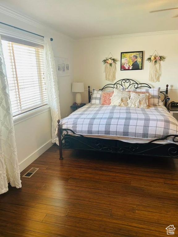 Bedroom with hardwood / wood-style floors, ornamental molding, and baseboards