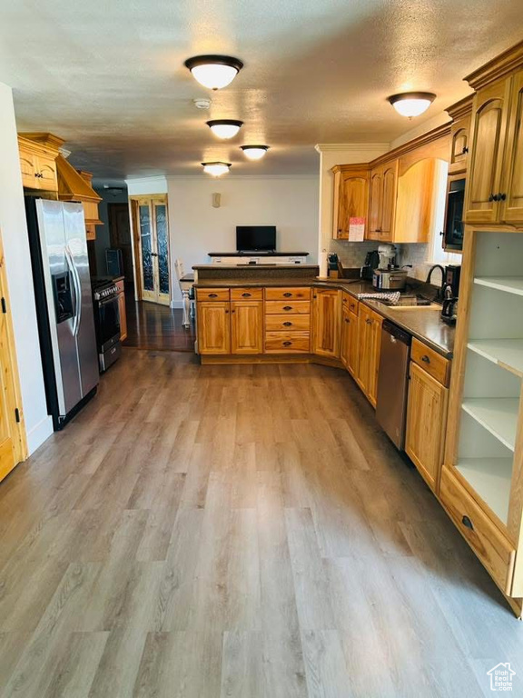 Kitchen featuring stainless steel appliances, dark countertops, a peninsula, and a sink