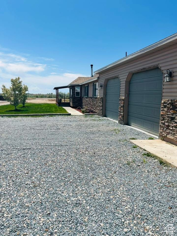 View of home's exterior featuring an attached garage, driveway, and stone siding