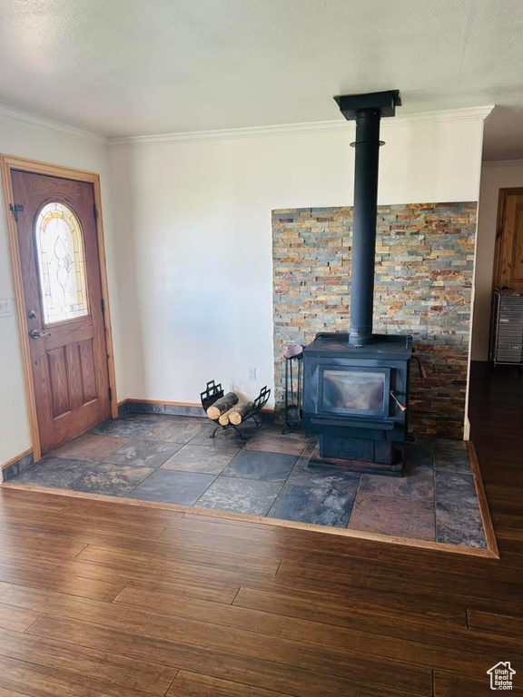 Entryway with hardwood / wood-style floors, baseboards, a wood stove, and ornamental molding